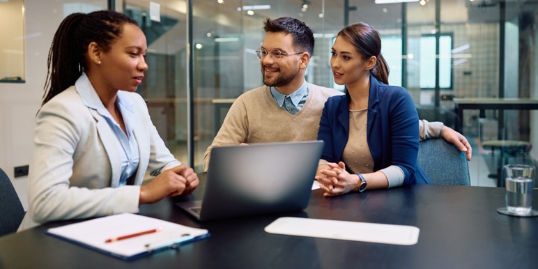 A young couple in consultation with a financial adviser, having an estate planning conversation.