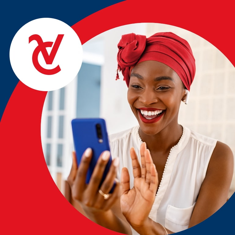 A happy young African woman wearing a vibrant headscarf smiles as she looks at her cell phone.
