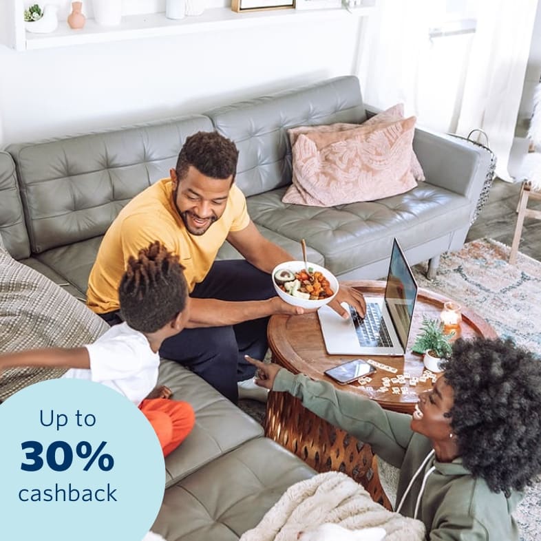 A happy young family sitting in their living area accessing their 30% cashback benefit on a laptop and feeling safe and secure that all their belongs are insured.