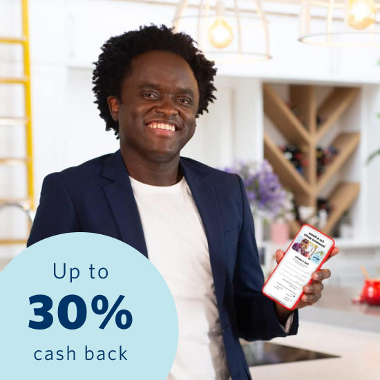 Comedian Tyson Ngubeni smiling in a house and displaying the Momentum App on this phone with a 30% cash back on car and home insurance premiums when joining Safety Returns.