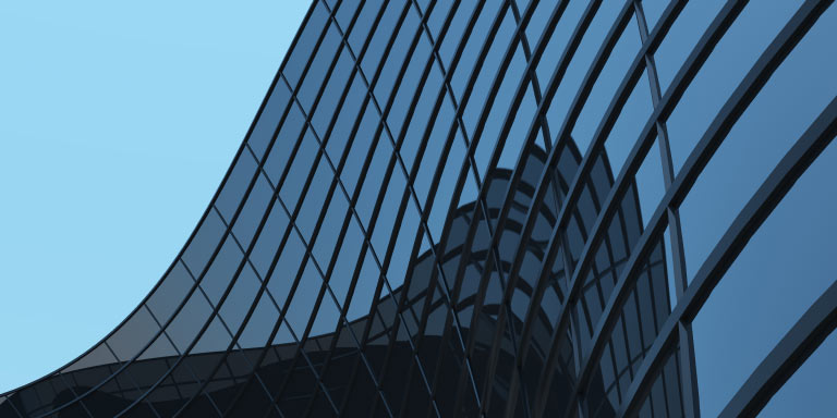 Modern architecture building in Vienna, Austria. A skyscraper with curved glass and steel exterior wall of a modern high-rise office building against a blue sky backdrop.