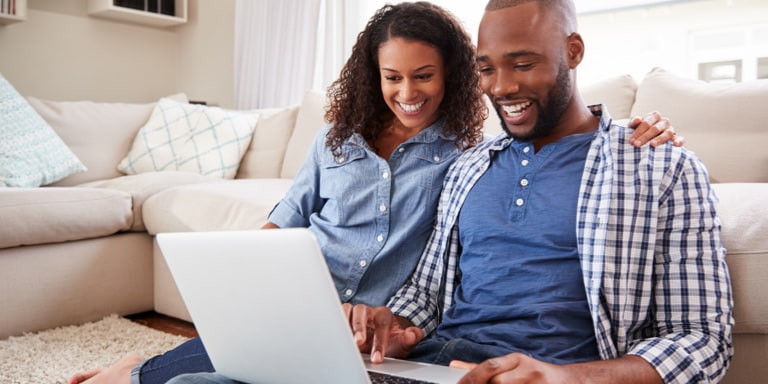 Young couple sitting on the floor of their living room, drafting their Will as part of the estate planning process.